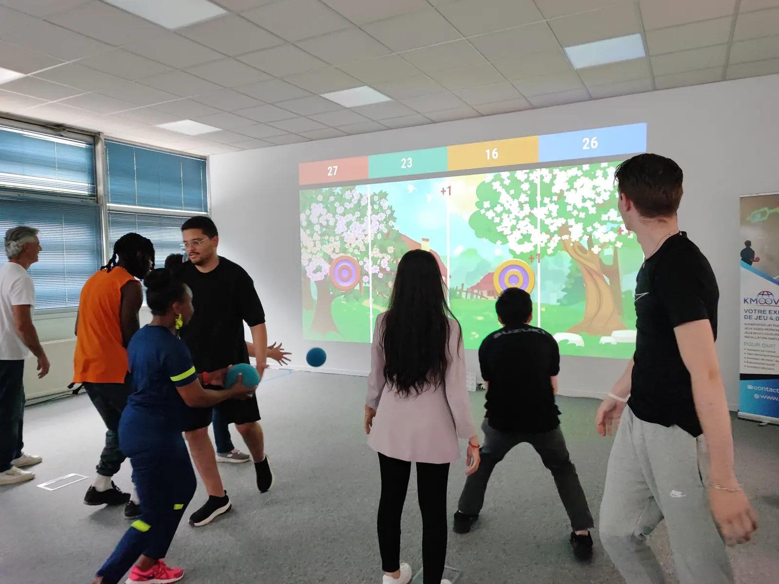 Équipe en team building autour du mur interactif Kmoove